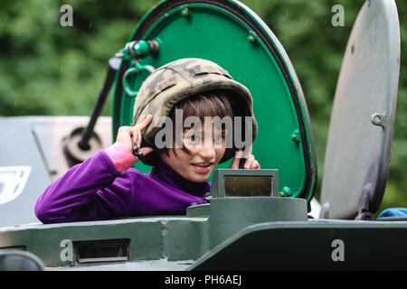 Un bambino polacco tenta su un casco dall'esercito polacco xv brigata meccanizzata durante una visualizzazione statica con gruppo di combattimento della Polonia a Giżycko, Polonia il 30 giugno 2018. Gruppo di combattimento della Polonia è un luogo unico e multinazionale di coalizione di Stati Uniti, Regno Unito, croato e soldati rumeni che servono con il polacco della XV Brigata meccanizzata come una forza di dissuasione a sostegno della NATO in avanti rafforzata presenza. Foto Stock