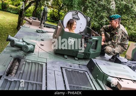 Un soldato polacco con xv brigata meccanizzata mostra un cittadino polacco un BMP-1 di combattimento della fanteria veicolo durante una visualizzazione statica con gruppo di combattimento della Polonia a Giżycko, Polonia il 30 giugno 2018. Gruppo di combattimento della Polonia è un luogo unico e multinazionale di coalizione di Stati Uniti, Regno Unito, croato e soldati rumeni che servono con il polacco della XV Brigata meccanizzata come una forza di dissuasione a sostegno della NATO in avanti rafforzata presenza. Foto Stock