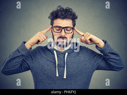 Uomo adulto in bicchieri tenendo le dita sulle tempie cercando di concentrarsi sul processo decisionale Foto Stock