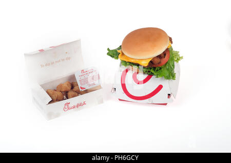 Chick-Fil-una Deluxe sandwich di pollo con lattuga, pomodoro e formaggio su un panino sulla parte superiore della confezione e una scatola di pepite di pollo con salsa di immersione su w Foto Stock