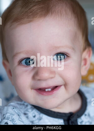 Carino redhead baby boy con gli occhi blu e due denti sorridente Foto Stock
