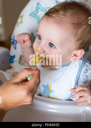 Alimentazione Mom carino redhead caucasian ragazzo con gli occhi blu vista superiore Foto Stock