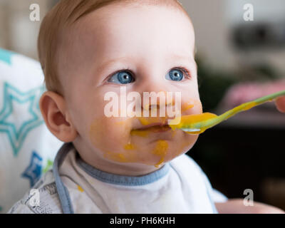 Alimentazione madre simpatico baby boy con gli occhi blu close up Foto Stock