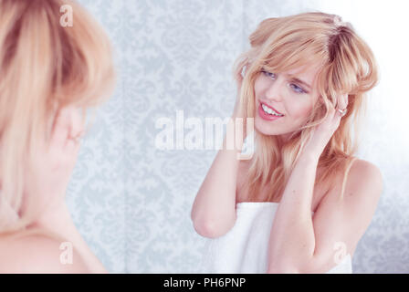 Giovane donna sorridente Tousling capelli in specchio Foto Stock