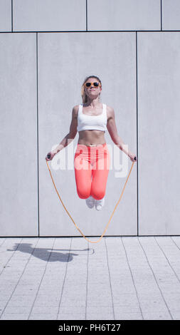 Energico giovane donna esercitando con salto con la corda Foto Stock