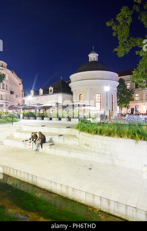 Baden: square Josefsplatz, ristorante in ex spa Josefsbad, giovani seduta, stream Mühlbach, Wienerwald, Vienna Woods, Niederösterreich, Lowe Foto Stock