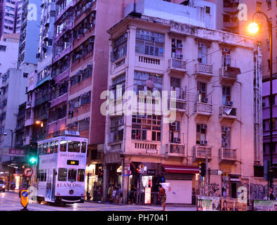 Il Tram che corrono lungo Des Voeux Road West , distretto occidentale al tramonto, Hong Kong Foto Stock