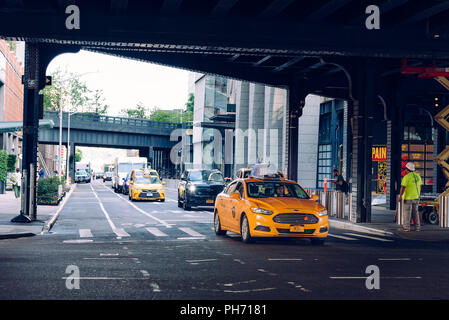 La città di New York, Stati Uniti d'America - 22 Giugno 2018: giallo taxi viaggiano sotto alta linea bridge in Manhattan Foto Stock