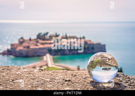 Sveti Stefan, Montenegro - Aprile 2018 : pietra miliare storica città vecchia riflessa nella grande trasparente sfera di vetro Foto Stock