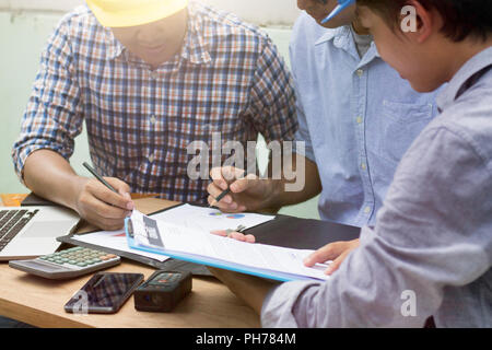 Gli ingegneri e i lavoratori riuniti e la pianificazione sul sito in costruzione. Foto Stock