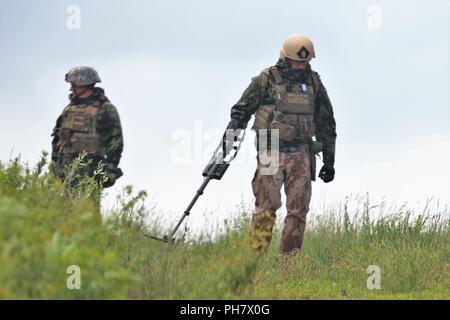 I membri del servizio con un militare straniero l'eliminazione degli ordigni esplosivi (EOD) team di eseguire la scansione di un pendio Giugno 26, 2018 sul tasso di caduta sulla zona sud di Post come parte della formazione in esercizio audace Warrior 2018 a Fort McCoy, Wis. quasi 60 aviatori di Guardia Nazionale unità in dieci Stati membri nonché di squadre di servizio internazionale i membri che fanno parte dell'eliminazione degli ordigni esplosivi squadre allenate a Fort McCoy per dodici giorni alla fine di giugno ai primi di Luglio come parte dell'esercizio. Anche la formazione ha avuto luogo nel campo Volk, Wis. durante il training e l'EOD personale scenari completati in convoglio operazioni, popolato Foto Stock