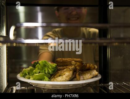 Airman 1. Classe Amanda Owen, quinta forza squadrone di supporto missile chef, imposta una piastra nella piastra più caldo a un missile alert facility in North Dakota, Giugno 25, 2018. Owen è uno dei molti aviatori che lavorano nel missile complesso in modo da fornire il nutrimento. Foto Stock