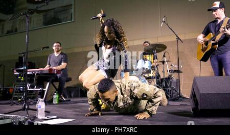 Un esercito di Iowa soldato della protezione nazionale fa pushups sul palco con il cantante Danika Portz al 2018 aiutante generale estivo di una serie di concerti presso il Camp Dodge manovra comune centro di formazione in Johnston, Iowa, il 21 giugno 2018. La serie di concerti avvolge il suo ottavo anno di libera settimanalmente concerti. Foto Stock