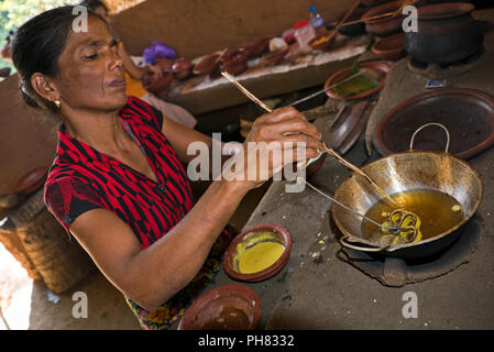 Posizione orizzontale ritratto di una dama preparandosi tradizionali dello Sri Lanka il cibo. Foto Stock