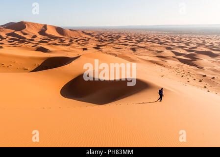 Donna in corsa in discesa, dune di sabbia rossa nel deserto, paesaggio di dune Erg Chebbi, Merzouga, Sahara, Marocco Foto Stock