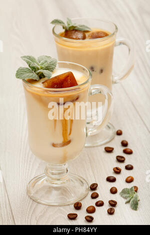 Due bicchieri di frullato delizioso () frullato al cioccolato con ghiaccio e foglie di menta su sfondo grigio Foto Stock