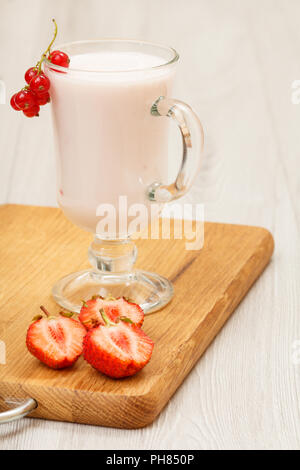 Delizioso yogurt alla fragola con le foglie di menta in vetro e fragole fresche sul tagliere di legno Foto Stock
