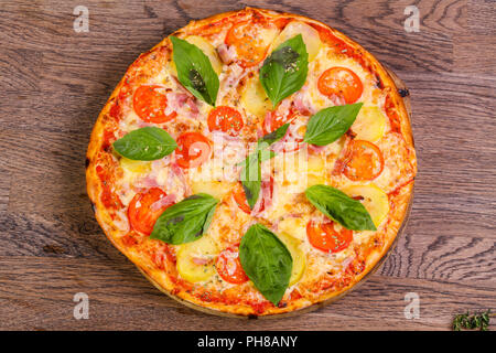 Pizza con prosciutto e patate servita il basilico Foto Stock