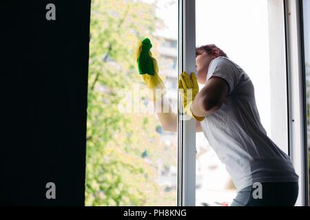 Bruna pulizia casalinga grande finestra sporca. Concetto di faccende di casa e appartamento di servizio. Foto Stock