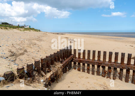 Di ferro arrugginito e storm erosione barriere di difesa su una sabbiosa spiaggia di Norfolk nel Regno Unito Foto Stock