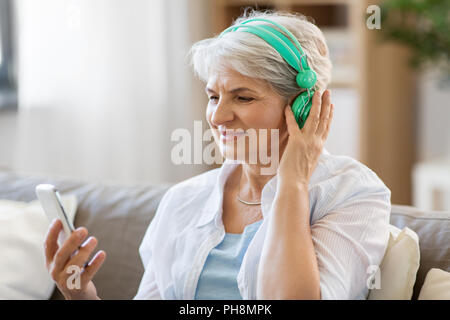 Senior donna nelle cuffie per ascoltare musica Foto Stock