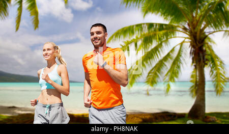 Coppia sorridente in esecuzione sulla spiaggia tropicale Foto Stock