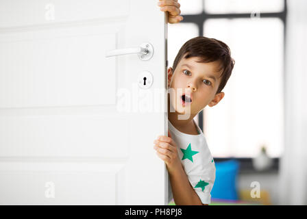 Sorpreso little boy dietro la porta di casa Foto Stock