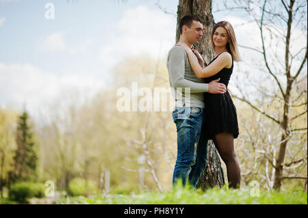 Felice coppia romantica in amore stare vicino ad albero e avvolgente. Foto Stock