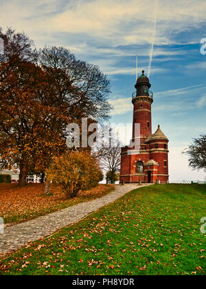 Leuchtturm Kiel-Holtenau. Deutschland. Il faro nel porto di Kiel. La Germania è una popolare attrazione turistica. Esso è stato originariamente costruito nel 1784 e il suo faro e torre è 20m di altezza. Fotografato su un tardo autunno il giorno in cui molti di foglie sono caduti da alberi che coprono l'erba e il percorso seguito. La giornata è luminosa con un po' di luce opaco formazioni di nubi. Foto Stock