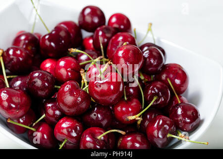 Close up fresche ciliege mature in una ciotola bianco Foto Stock