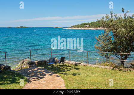 Tipica spiaggia rocciosa con due sedie in Istria Foto Stock