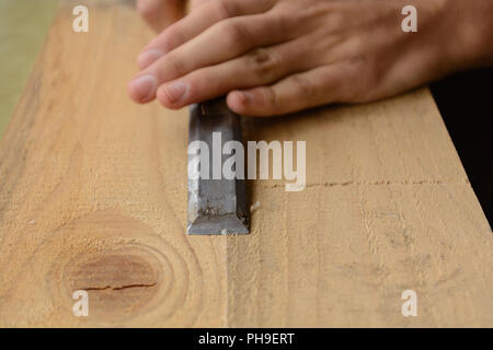 La falegnameria lavora con scalpelli una tavola di legno - close-up Foto Stock