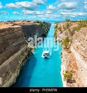 Uno splendido scenario del Canale di Corinto in una luminosa giornata di sole contro un cielo blu con nuvole bianche. White Ship floating tra le rocce Foto Stock