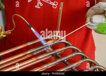 Ingegnere di lavoro su tubi di rame - close up di brasatura Foto Stock
