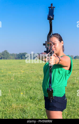 Donna mirando con arco e frecce nella natura Foto Stock