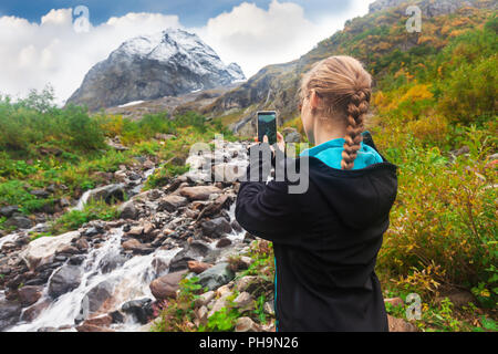 Donna di scattare una foto di mountin sullo smartphone Foto Stock