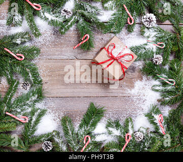 Snowy rami d abete e candy canes su rustiche tavole in legno Foto Stock