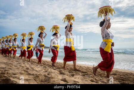 Una linea di donna balinese offerte di trasporto sulle loro teste a Melasti, la più grande massa Cerimonia di purificazione in Bali, tenuto 3 giorni prima del Nyepi. Foto Stock