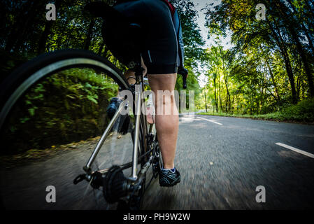 Ciclista femmina in bicicletta lungo una strada rurale in Bowland, Lancashire, Regno Unito. Foto Stock