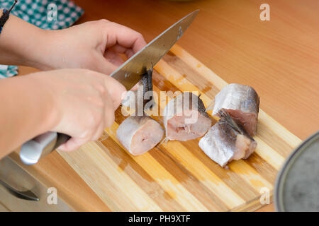 Mani femminili con Coltello per affettare il nasello pesce Foto Stock