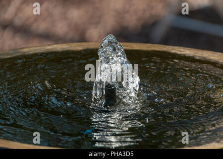 Acqua limpida che viene spinto fuori dalla parte superiore del calcestruzzo di una fontana di acqua Foto Stock