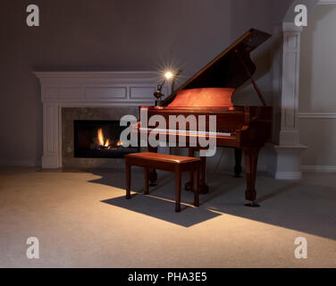 Un pianoforte con luce per leggere e incandescente camino durante la sera Foto Stock