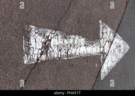 Una vista ravvicinata di un dipinto di bianco di strada la freccia mostra la direzione del traffico Foto Stock