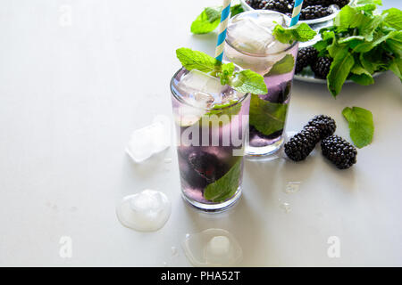 Limonata Fresca con blackberry, ghiaccio e menta su grigio Sfondo di legno. Bevanda estiva concept Foto Stock