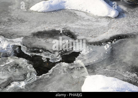 Ghiaccio e neve su una rana, scongelamento del fiume Foto Stock
