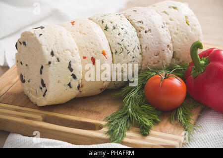Varietà di casa fatta di formaggio e paprica e le erbe e i pomodori su una tavola di legno. messi in salamoia cagliata di formaggio bianco con verdure sul tavolo Foto Stock