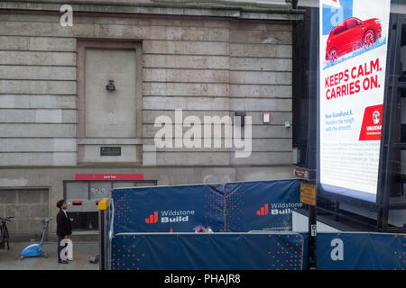 Un soccorritore occasionale viste di un digitale pubblicità Affissioni a London Bridge a Southwark, il 29 agosto 2018, a Londra, in Inghilterra. Foto Stock