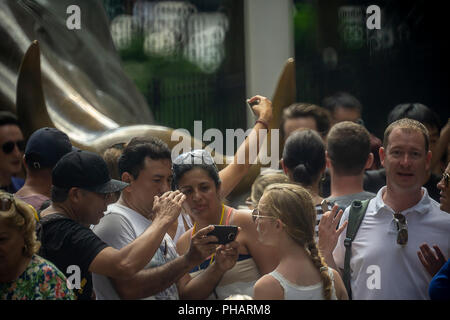 Orde di turisti cluster intorno e posare per le foto di fronte al Wall Street Bull, artista Arturo DiModica, su Broadway in Lower Manhattan a New York il giovedì 30 agosto, 2018. Il mercato azionario è avente la più lunga bull run nella storia, a partire dal 9 marzo 2009 come la grande recessione si è conclusa. (Â© Richard B. Levine) Foto Stock