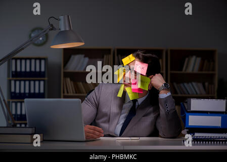 Uomo d'affari che soggiornano in ritardo per ordinare le priorità Foto Stock