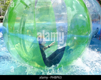 La donna in una sfera di plastica su acqua Foto Stock